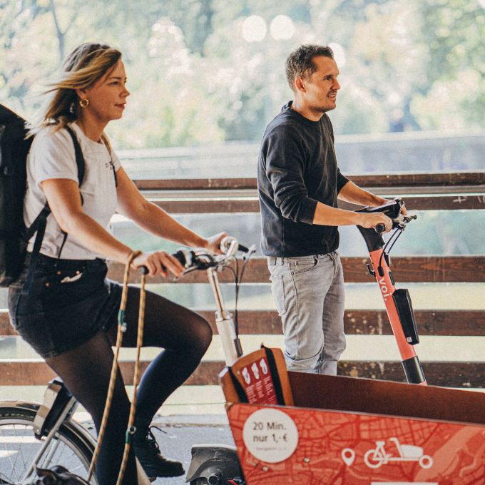 Die 2 Art Directors unserer Kreativagentur auf VAG Lastenfahrrad und Voi Scooter.